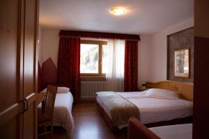 a hotel room with two beds and a window at Baita Scaia in Cogolo
