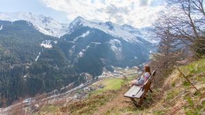 una donna seduta su una panchina che domina una valle di montagna di Paulnhof a Brennero