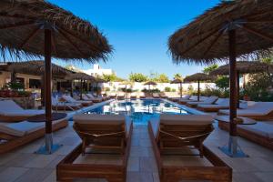 een resort met een zwembad met stoelen en parasols bij Villa Angira in Kamari