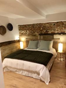 a bedroom with a large bed with a stone wall at Le 20 in Cintegabelle