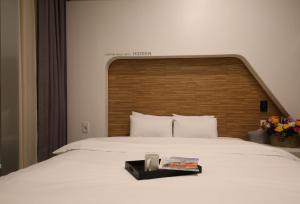 a bedroom with a large white bed with a wooden headboard at Urban Stay Hotel in Gwangju