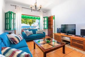 een woonkamer met een blauwe bank en een tv bij Casajardin in Playa Honda