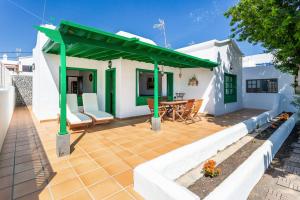 a patio with a green roof with a table and chairs at Casajardin in Playa Honda