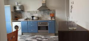 a kitchen with blue cabinets and a washing machine at Apartamento Sol deluxe Suances in Suances