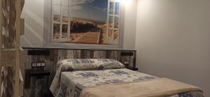 een slaapkamer met een bed met een foto aan de muur bij Apartamento Sol deluxe Suances in Suances