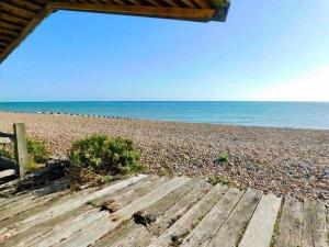 a beach with a wooden pathway leading to the ocean at Beautiful 4 Bed Beach House in Pevensey