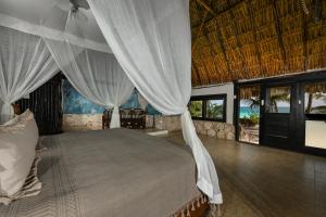 a bedroom with a bed with white curtains at Diamante K - Inside Tulum National Park in Tulum