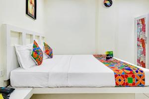 a bedroom with a white bed with colorful pillows at FabHotel Colors Service Apartment in Chennai