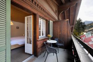 un balcón de una casa con mesa y sillas en Hotel-Restaurant zum Gade, en Lenk