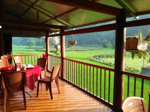 a porch with a table and chairs and a view of a field at Tran Xuan Homestay Ba Be Village in Ba Be
