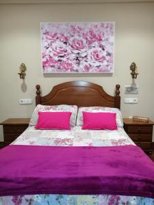 1 dormitorio con cama con sábanas moradas y almohadas rosas en Hostal Mizmaya, en Hoznayo
