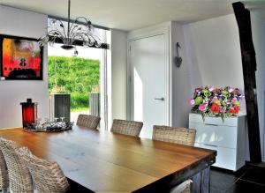 a dining room with a wooden table and flowers at Markermeerlogies in Bovenkarspel