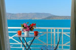 una mesa con flores en un balcón con vistas al océano en Margarita's Seafront Luxury Apartment en Eloúnda