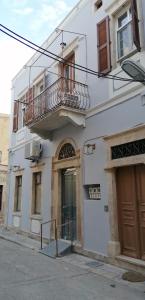un edificio bianco con balcone e porta di THEOS APARTMENTS a Calimno (Kalymnos)