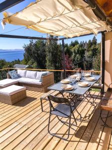 a table and chairs on a deck with an umbrella at Ventanas Al Lago in San Carlos de Bariloche