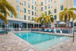 a swimming pool in front of a building with palm trees at Staybridge Suites St. Petersburg FL by IHG in St. Petersburg