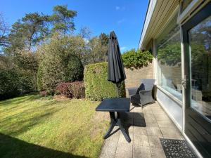 a patio with an umbrella and a table and a chair at Bungalows Hoefbos in Otterlo