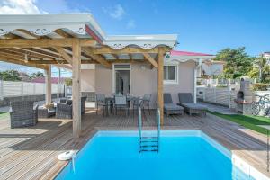 a wooden deck with a pool and a pergola at Villa belle lune in La Trinité