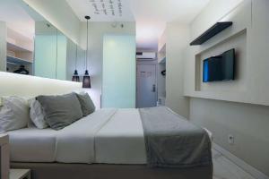 Nobile Hotel Copacabana Design في ريو دي جانيرو: غرفة نوم بسرير وتلفزيون على جدار