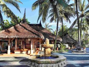 a large stone building with palm trees and palm trees at Novotel Lombok Resort & Villas in Kuta Lombok