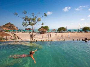 a person swimming in the water at a beach at Novotel Lombok Resort & Villas in Kuta Lombok