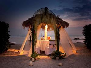 a table on the beach with a white table cloth at Novotel Lombok Resort & Villas in Kuta Lombok