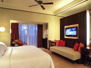 a hotel room with a bed and a couch at Novotel Lombok Resort & Villas in Kuta Lombok
