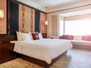 a bedroom with a large white bed and a window at Novotel Lombok Resort & Villas in Kuta Lombok