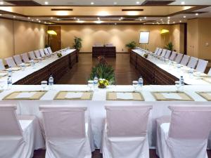 a set of long tables in a room with white chairs at Novotel Lombok Resort & Villas in Kuta Lombok