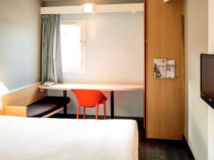 a small room with a table and a red chair at ibis Dieppe Le Val Druel in Dieppe