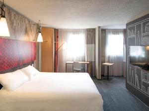 リモージュにあるibis Limoges Nordの白いベッドとテレビが備わるホテルルームです。