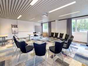 a meeting room with chairs and a table and a board at Mercure Hotel Köln West in Cologne