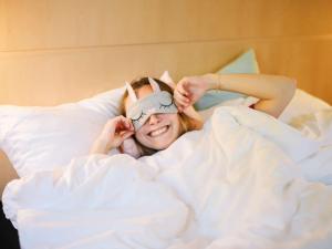 a woman laying in bed with a mask on her face at ibis Aix en Provence in Aix-en-Provence