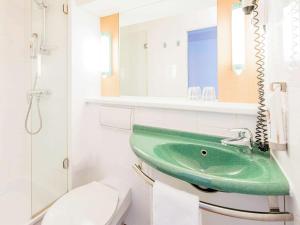 uma casa de banho com um lavatório verde e um WC em ibis Paderborn City em Paderborn