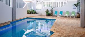 - une piscine avec des chaises dans la chambre dans l'établissement Eatons Hill Hotel, à Brisbane