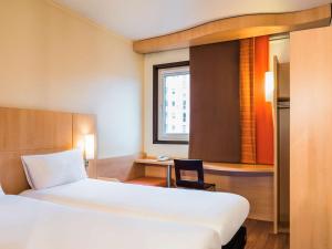 a bedroom with a bed and a desk and a window at ibis Paris Pont de Suresnes Longchamp in Suresnes