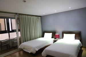 a bedroom with two beds and a table and a window at Residence Hotel Lamia in Daejeon