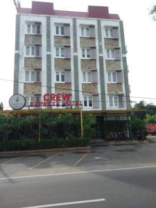 een groot gebouw met een bord op een parkeerplaats bij CREW EXPRESS Hotel in Lubukpakam