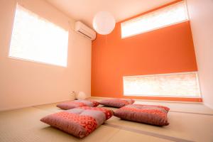 three beds in a room with orange walls and windows at Fuji Kurasu 響 in Fujikawaguchiko
