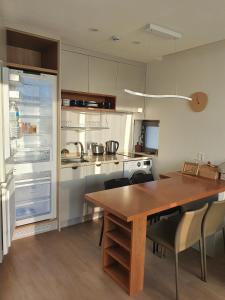 a kitchen with a refrigerator, stove, sink and a table at Aewol Bada Town House in Jeju