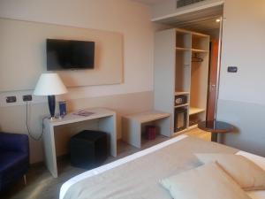 
a bedroom with a bed, desk and a television at First Hotel Malpensa in Case Nuove
