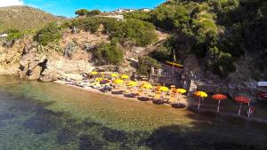 a beach with chairs and umbrellas on the beach at Hotel Dino in Capoliveri