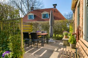 un patio con mesa, sillas y sombrilla en Appartement Torenzicht - Leeuwarden, en Marssum