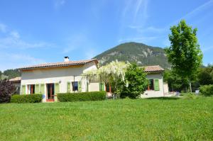 a house in a field with a mountain in the background at Le gîte de Valérie côté jardin in Die