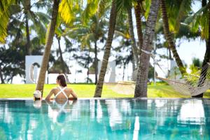 uma mulher de biquíni sentada numa piscina em Raffles Hainan Clear Water Bay em Sanya