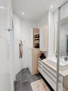a white bathroom with a sink and a shower at Lake View Apartment Seecorso in Velden am Wörthersee