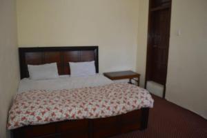 a bedroom with a large bed with a wooden headboard at Shah Guest House in Gilgit
