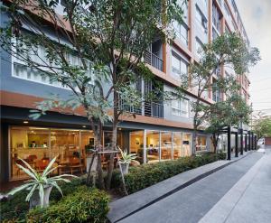 een gebouw met glazen ramen en bomen op een straat bij The Grass Serviced Suites in Pattaya