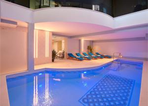 a large swimming pool with blue chairs in a building at Hotel Cvita in Split