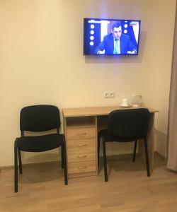 a room with two chairs and a desk with a tv on the wall at Raasiku Hotell in Raasiku